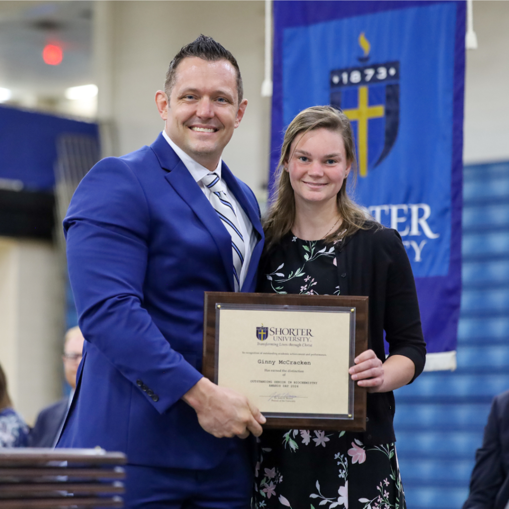 Dr. Clint Helms and Ginny McCracken standing with the award.