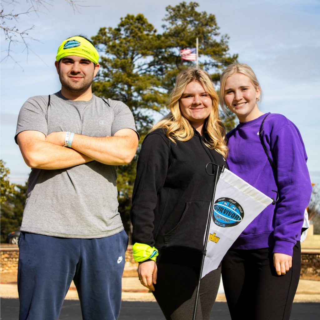 A male and two females standing with their survivor flag