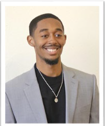 A young man wearing a suit smiling at the camera